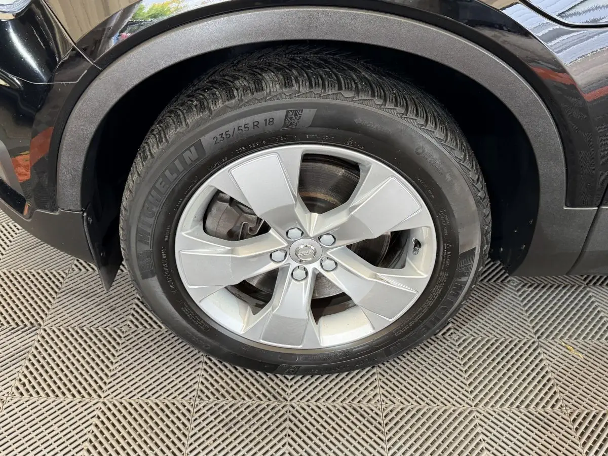 Gros plan sur la roue avant droite noire d’un Volvo XC40 Recharge T5 avec jante alliage argentée et pneu Michelin.