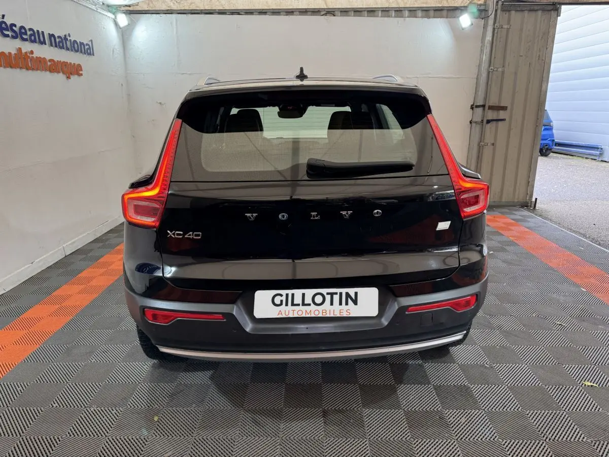 Vue arrière d’un Volvo XC40 noir avec feux arrière en forme de L et logo Volvo visible sur le hayon.