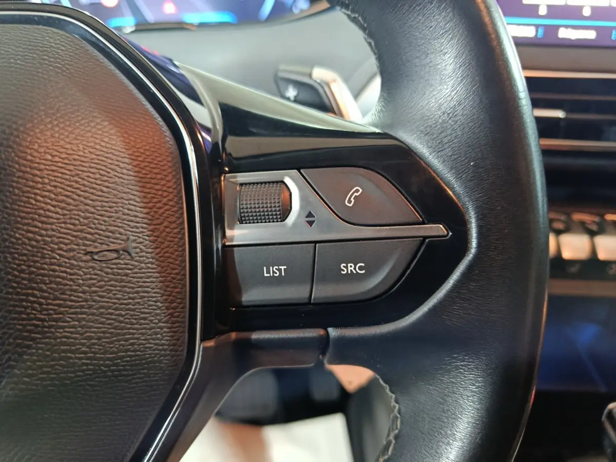 Gros plan sur les commandes gauche du volant cuir noir du Peugeot 3008 marron, avec boutons LIST et SRC visibles.