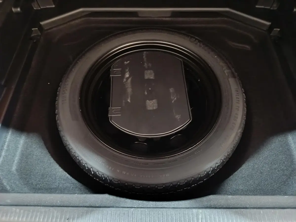 Gros plan sur la roue de secours noire dans le coffre du Peugeot 3008 marron, vue de dessus.