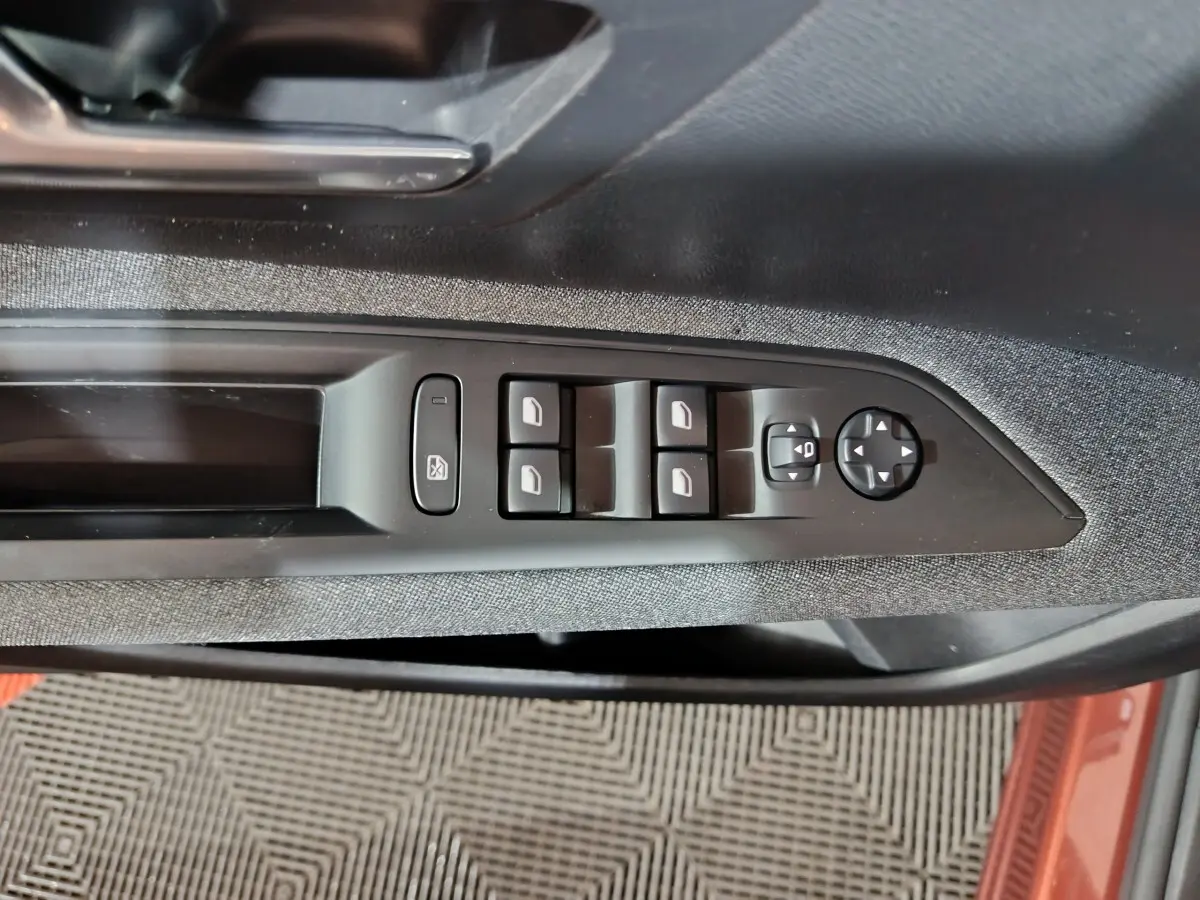 Vue rapprochée de la commande des vitres électriques sur la porte côté conducteur du Peugeot 3008 marron 2019.