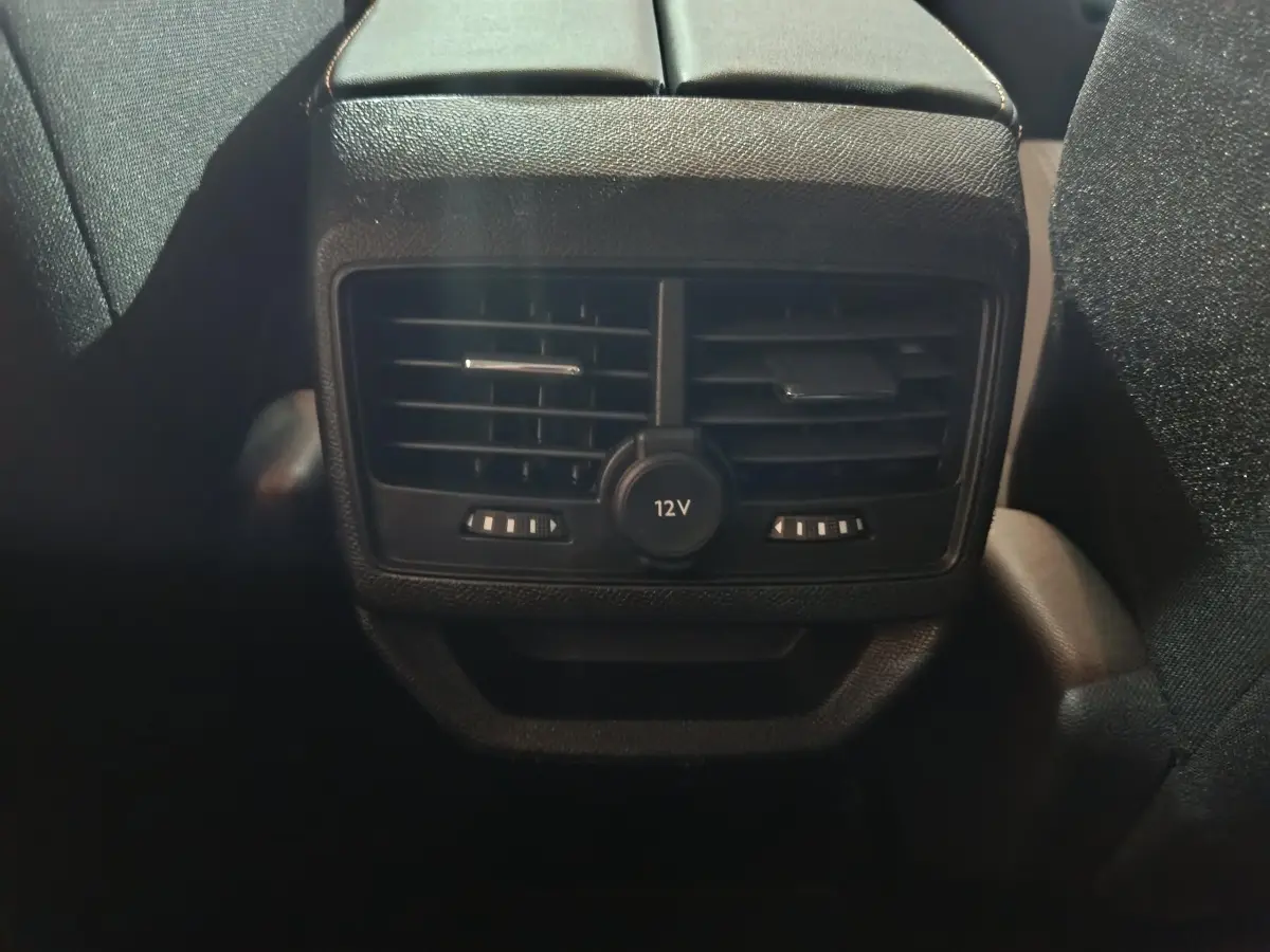 Vue rapprochée des aérateurs arrière noirs et prise 12V du Peugeot 3008 marron, côté intérieur passagers arrière.