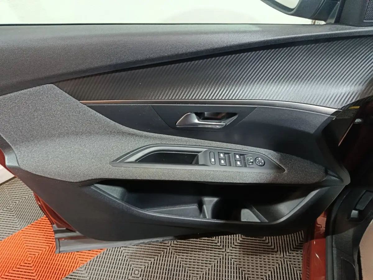 Vue intérieure du panneau de porte côté conducteur de la Peugeot 3008 marron, avec commandes électriques des vitres et rétroviseurs.