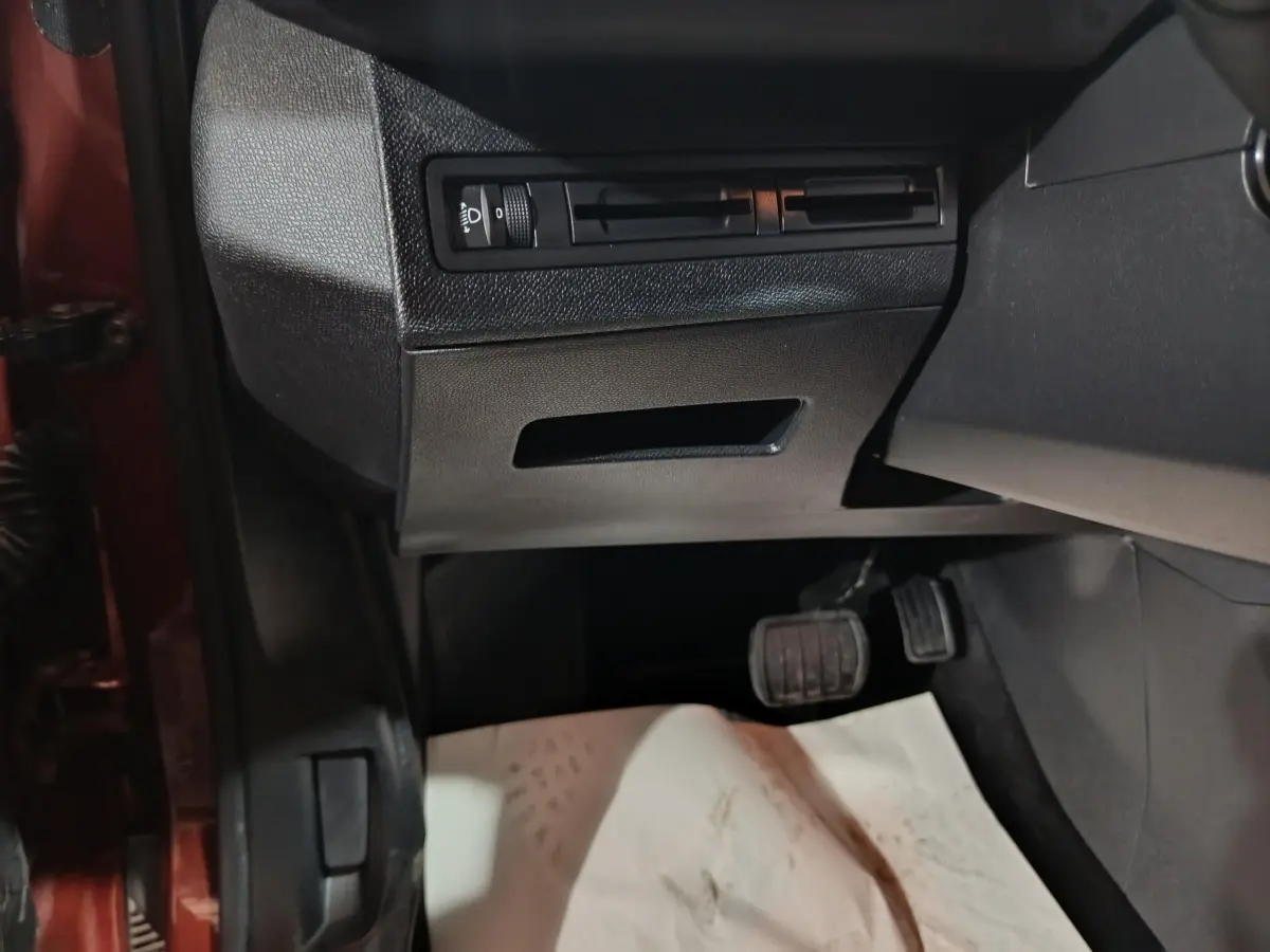 Vue intérieure côté conducteur du Peugeot 3008 marron, montrant les pédales et commandes d'éclairage sous le tableau de bord.