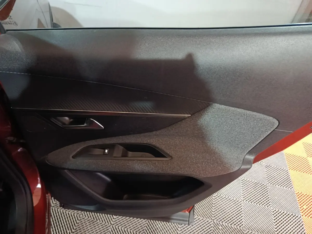 Vue intérieure côté gauche de la porte avant marron du Peugeot 3008 avec commandes de vitres et poignée intégrée.