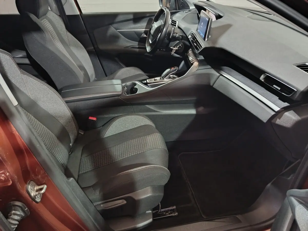 Vue intérieure côté conducteur du Peugeot 3008 marron, mettant en valeur les sièges tissu, le volant cuir multifonctions et l’écran tactile central.