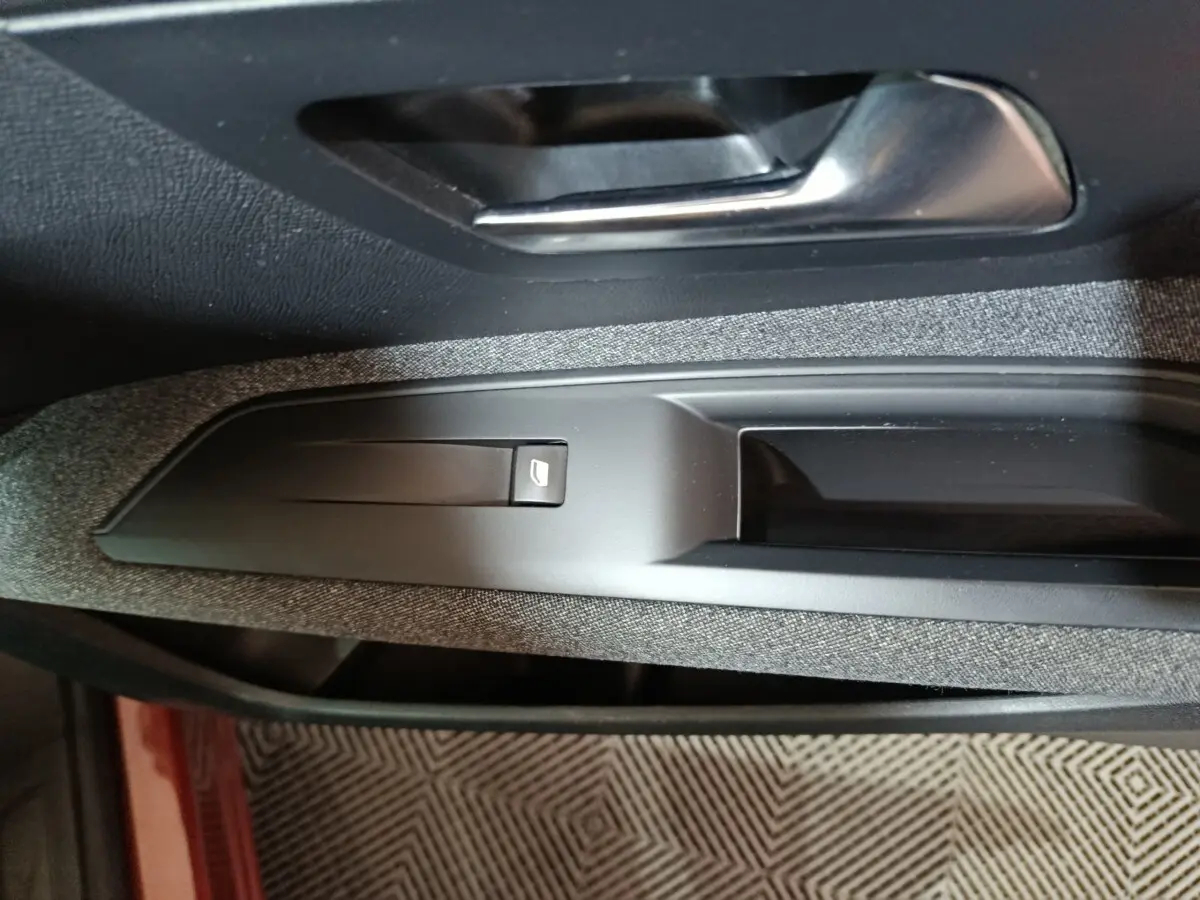 Détail de la commande de lève-vitre côté conducteur sur la porte intérieure d’un Peugeot 3008 marron.