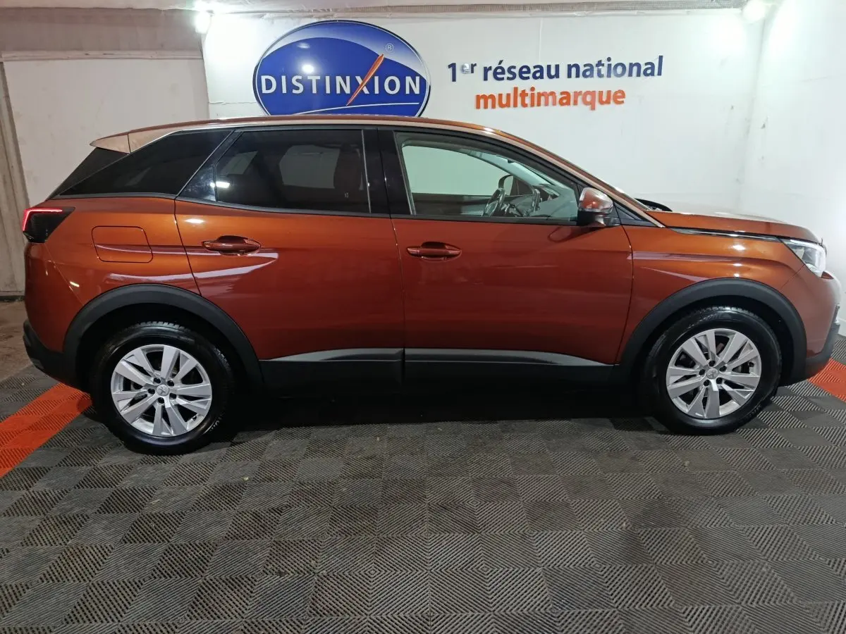 Vue de profil côté gauche d'un Peugeot 3008 marron 2019 avec toit noir et jantes alliage en intérieur showroom.