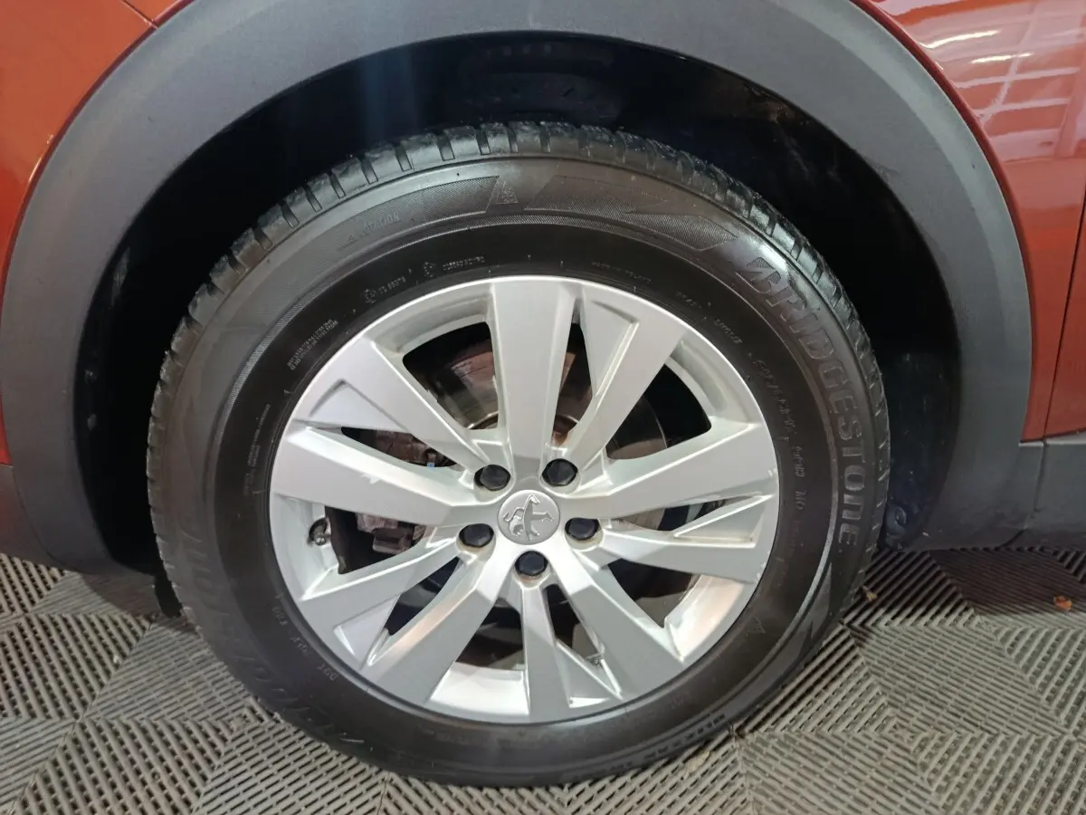 Gros plan sur la roue avant gauche avec jante argentée du Peugeot 3008 marron, version BlueHDi 130 de 2019.