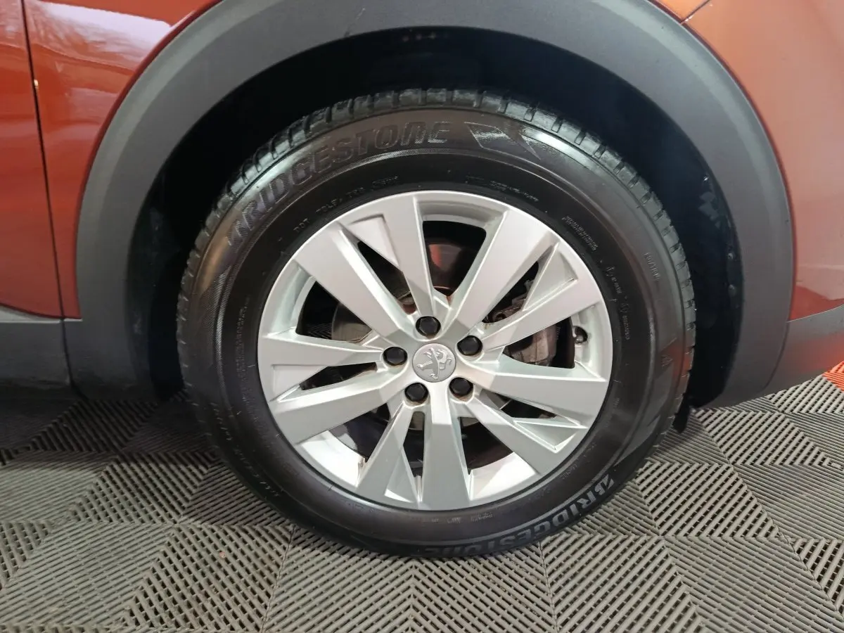 Gros plan sur la roue avant gauche d’un Peugeot 3008 marron, avec jante alliage argentée et pneu Bridgestone.