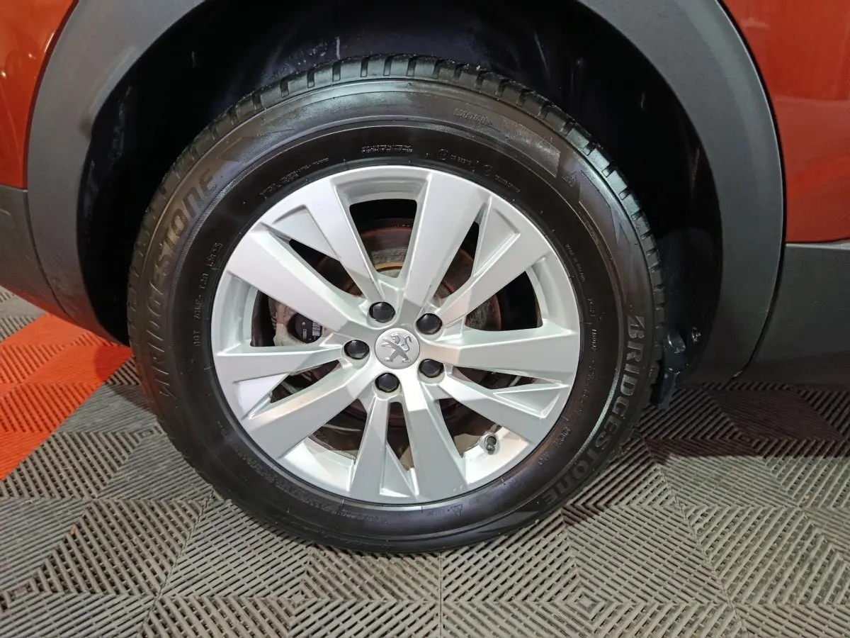 Gros plan sur la roue avant droite d’un Peugeot 3008 marron, jante alliage argentée avec logo lion central.