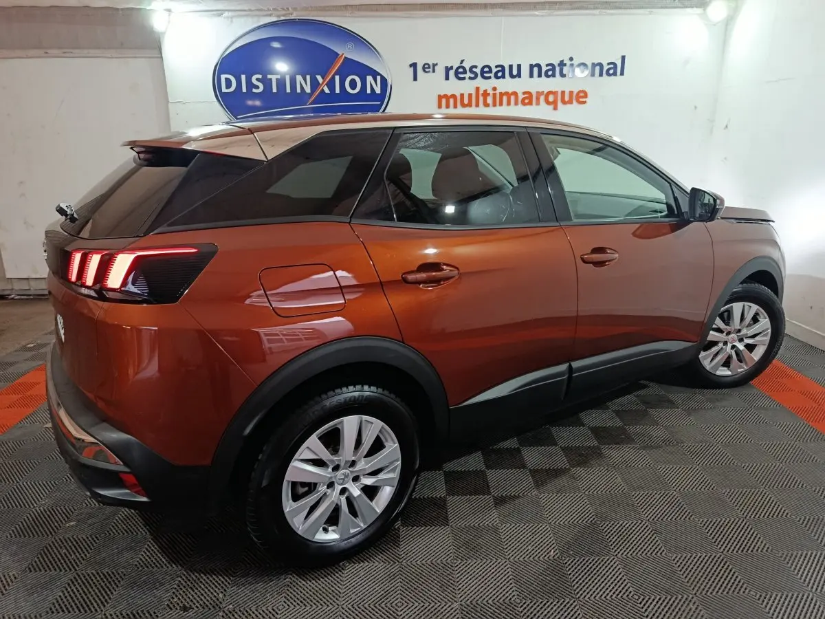 Peugeot 3008 marron vue 3/4 arrière droit, feux arrière LED allumés, toit noir et jantes argentées.