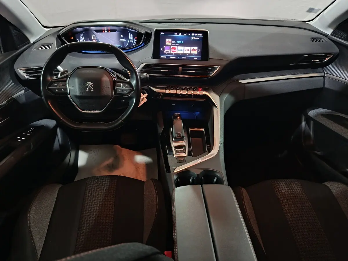 Vue intérieure frontale du tableau de bord et volant cuir du Peugeot 3008, avec écran tactile central allumé.