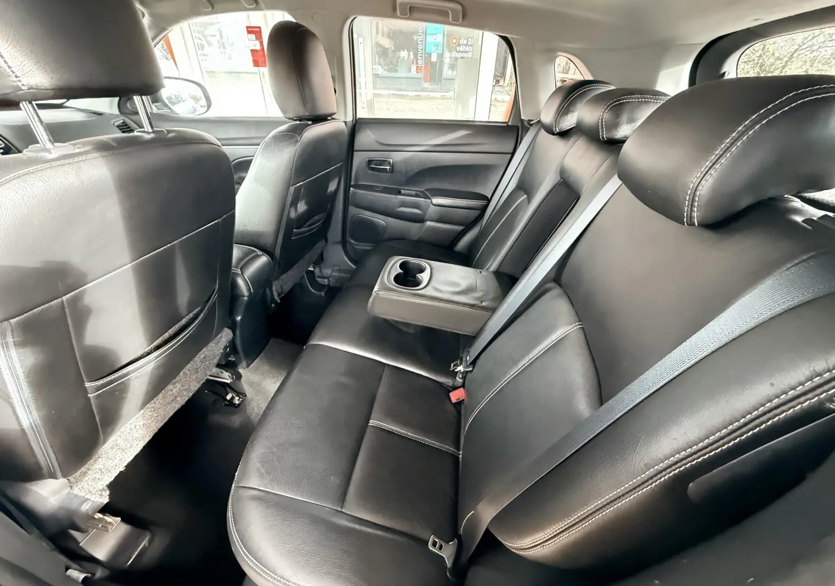 Vue intérieure arrière montrant les sièges en cuir noir avec accoudoir central et porte-gobelets du Mitsubishi ASX.
