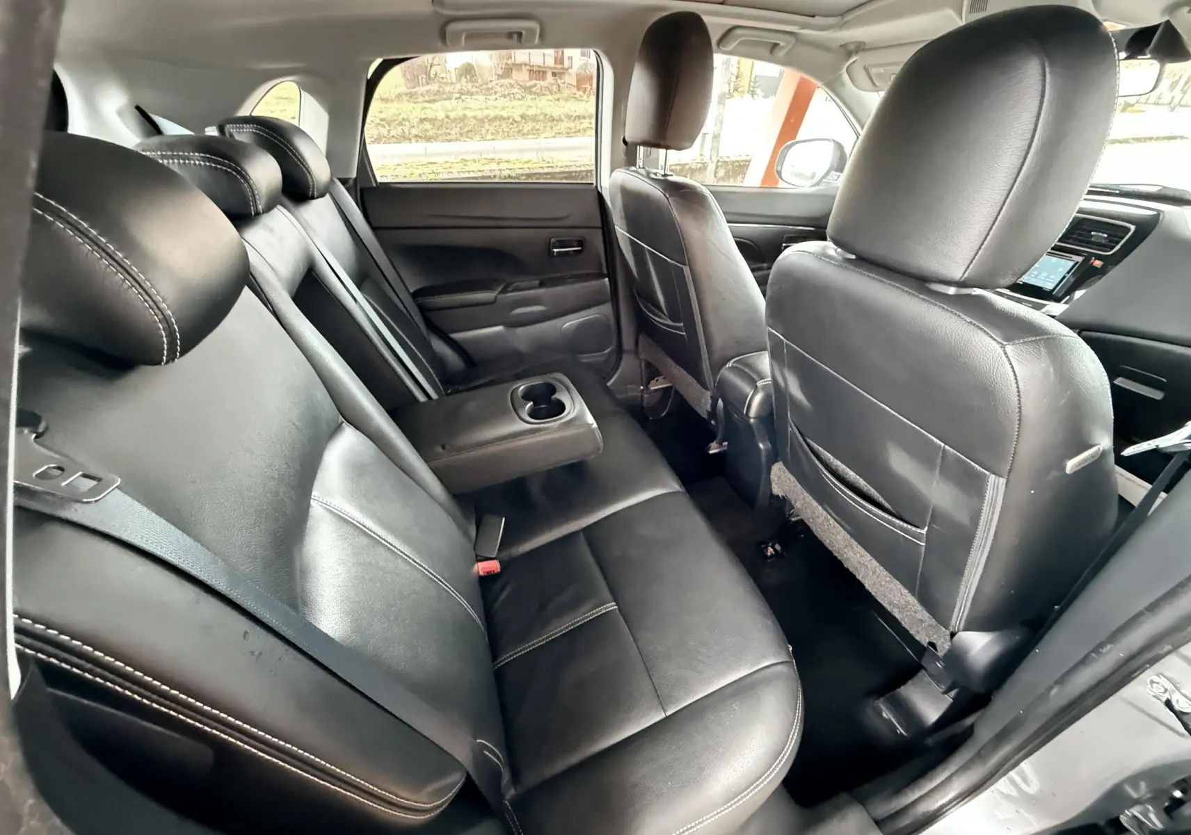 Vue intérieure arrière du Mitsubishi ASX 2015 montrant les sièges en cuir noir avec accoudoir central déployé.