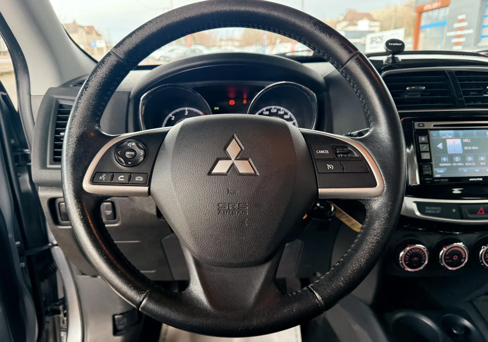 Vue centrée sur le volant noir du Mitsubishi ASX 2015 avec tableau de bord et console centrale visibles.