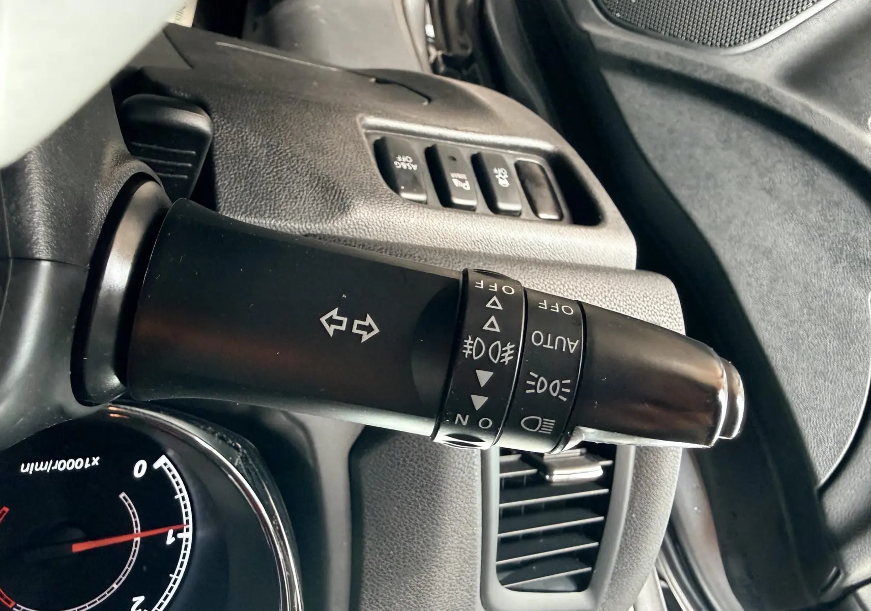 Gros plan sur la commande des clignotants et phares du tableau de bord d’un Mitsubishi ASX gris de 2015.