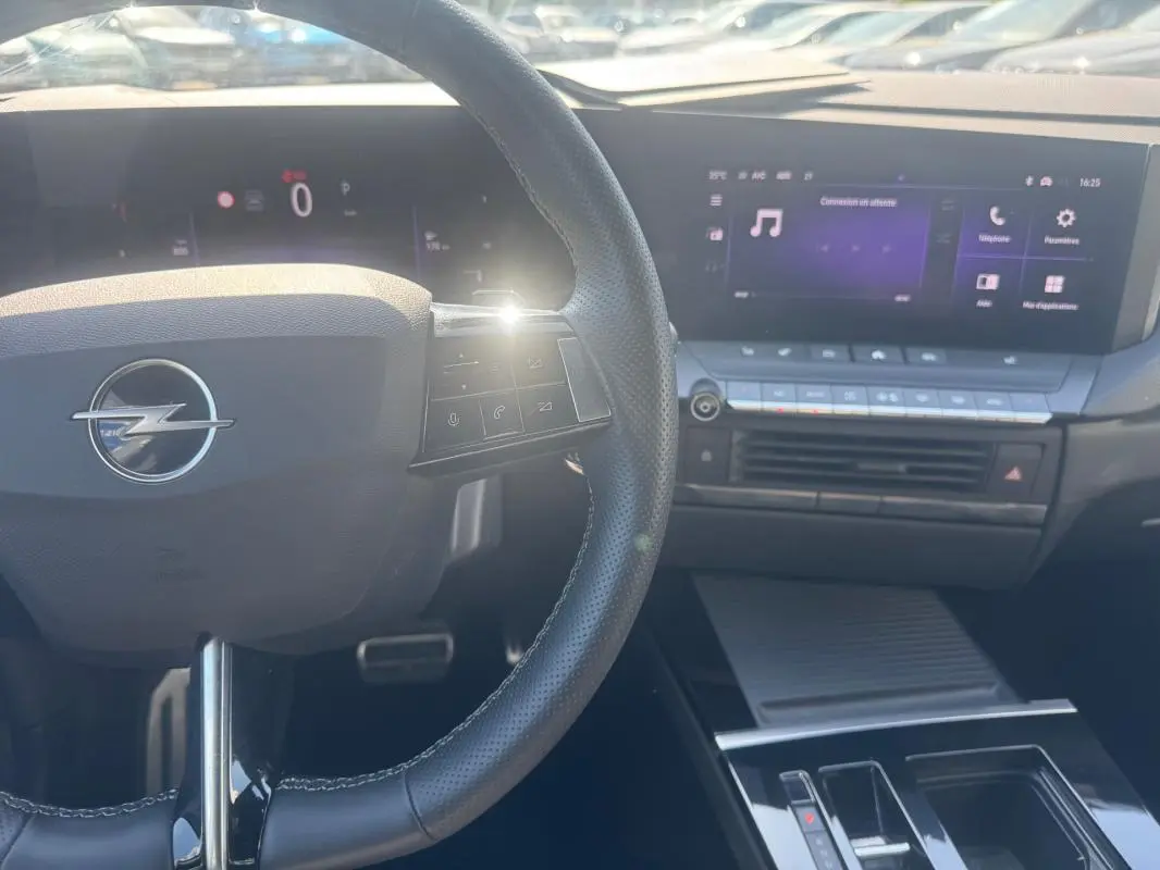 Vue rapprochée de l'intérieur de l'Opel Astra 2024, volant cuir noir avec commandes et écran tactile central lumineux.