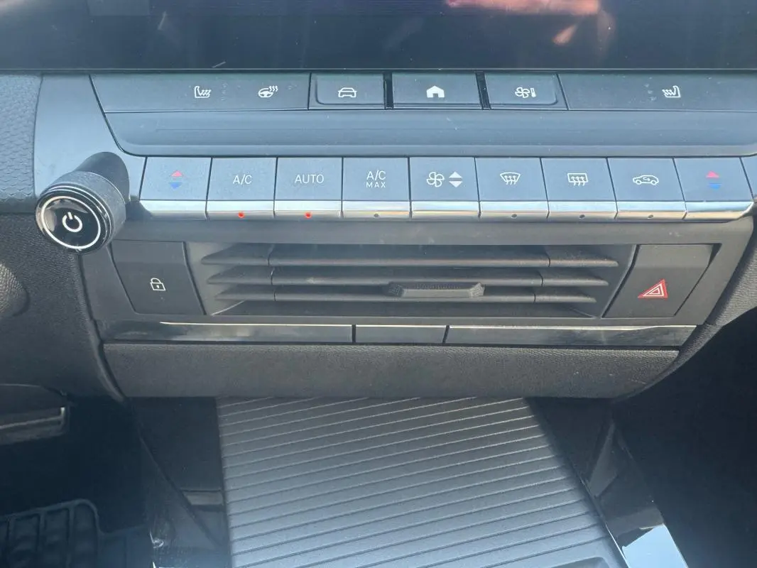 Vue rapprochée de la console centrale noire de l’Opel Astra 2024, avec commandes climatisation et boutons fonctionnels.