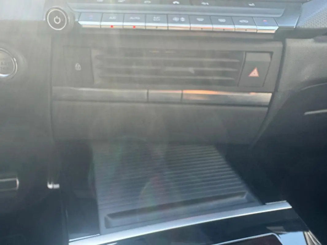 Vue intérieure centrée sur la console centrale noire de l'Opel Astra 2024 avec commandes climatisation et rangement fermé.