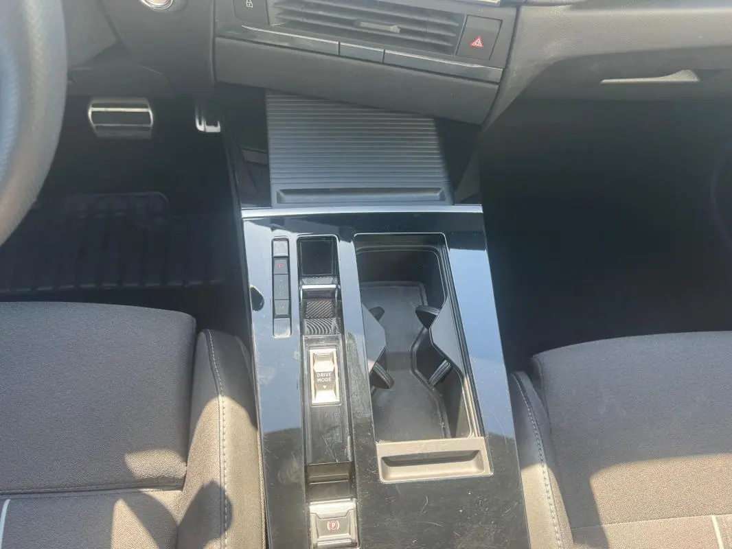 Vue intérieure centrée sur la console centrale noire de l'Opel Astra 2024 avec commandes de boîte auto et porte-gobelets.