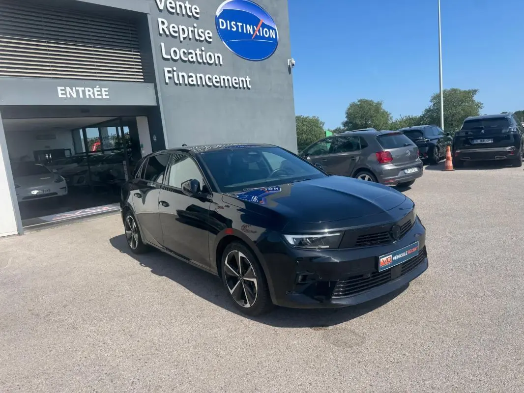 Opel Astra noire vue en 3/4 avant droit, avec jantes alliage 17 pouces et calandre moderne, stationnée devant un bâtiment.