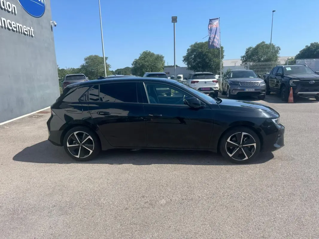 Opel Astra noire vue de profil côté gauche, avec jantes alliage 17 pouces et vitres surteintées.