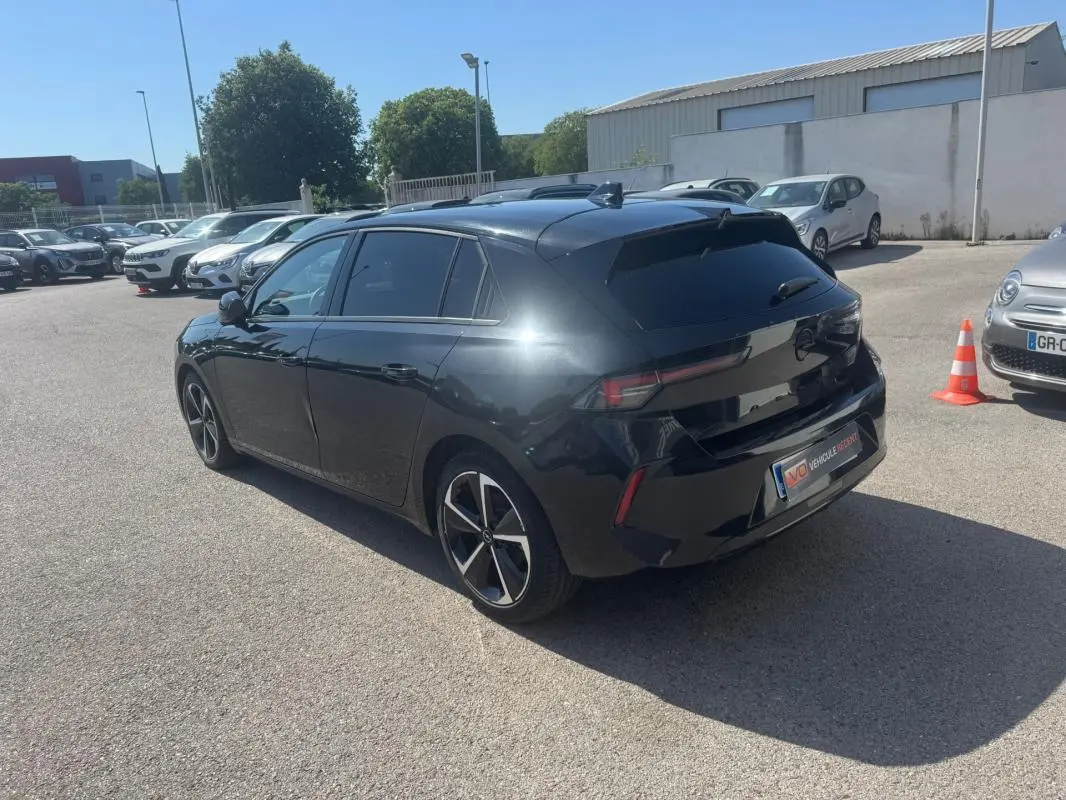Opel Astra noire vue 3/4 arrière droit, avec vitres surteintées et jantes alliage 17 pouces.