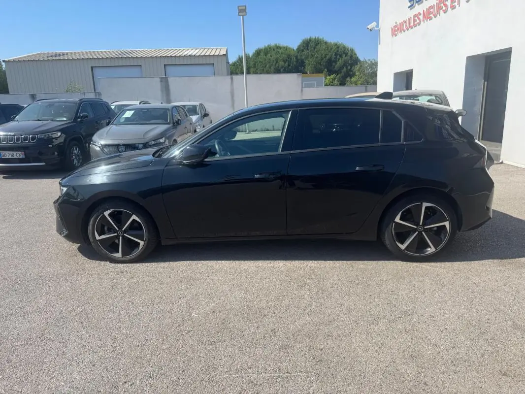 Opel Astra noire vue de profil côté gauche, avec jantes alliage 17 pouces et vitres surteintées.