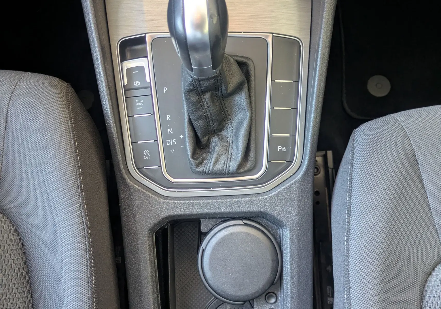 Vue plongeante sur la console centrale de la Volkswagen Golf Sportsvan noire, avec levier de vitesse DSG et porte-gobelets.