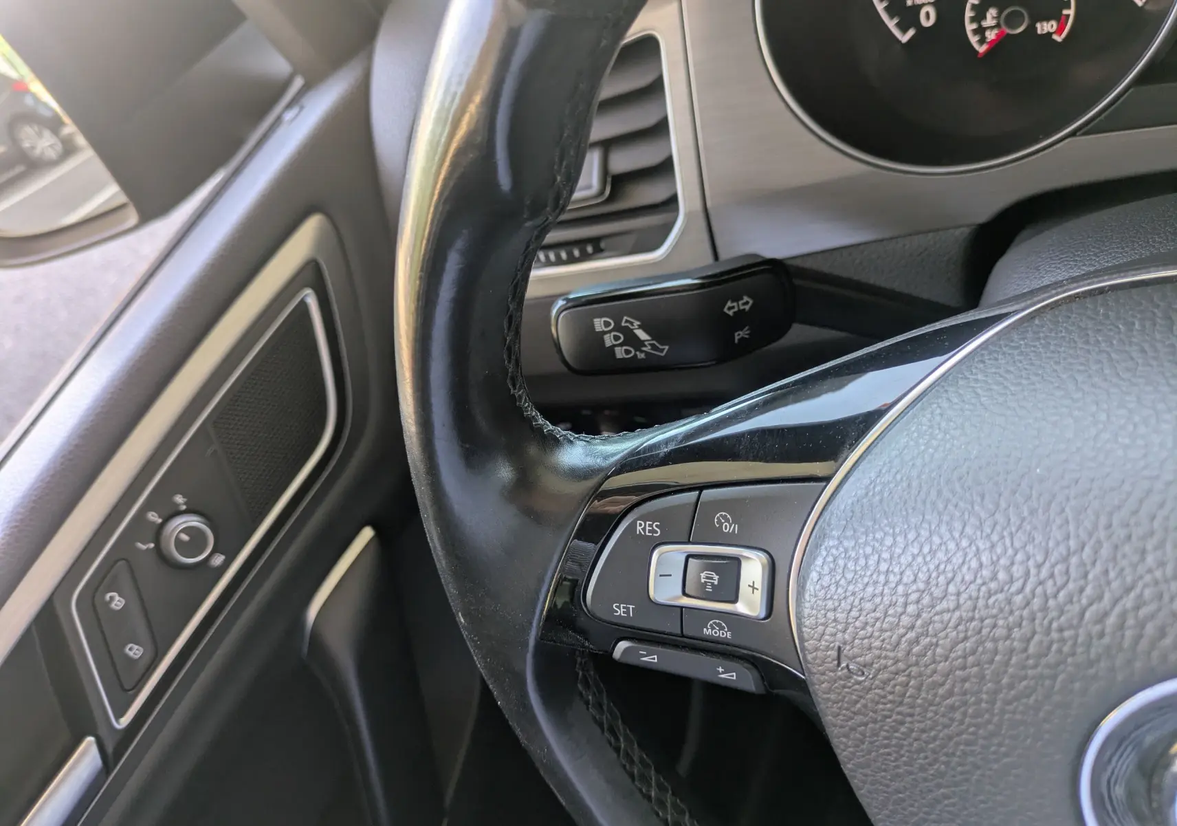 Gros plan sur le volant noir et la commande de régulateur de vitesse côté gauche du Volkswagen Golf Sportsvan 2014.