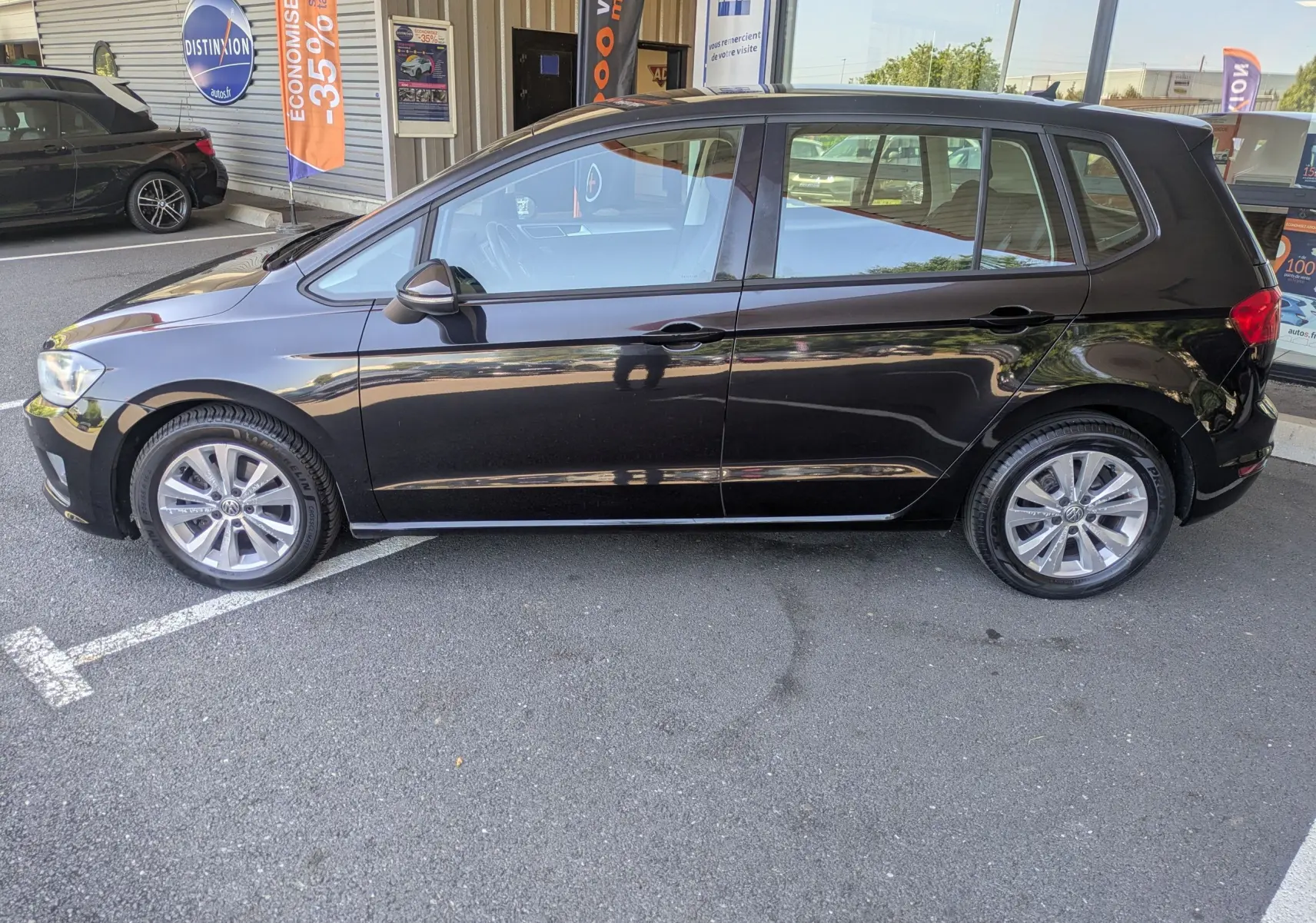 Vue de profil côté gauche d'une Volkswagen Golf Sportsvan noire de 2014, finition Confortline avec jantes alliage 16 pouces.