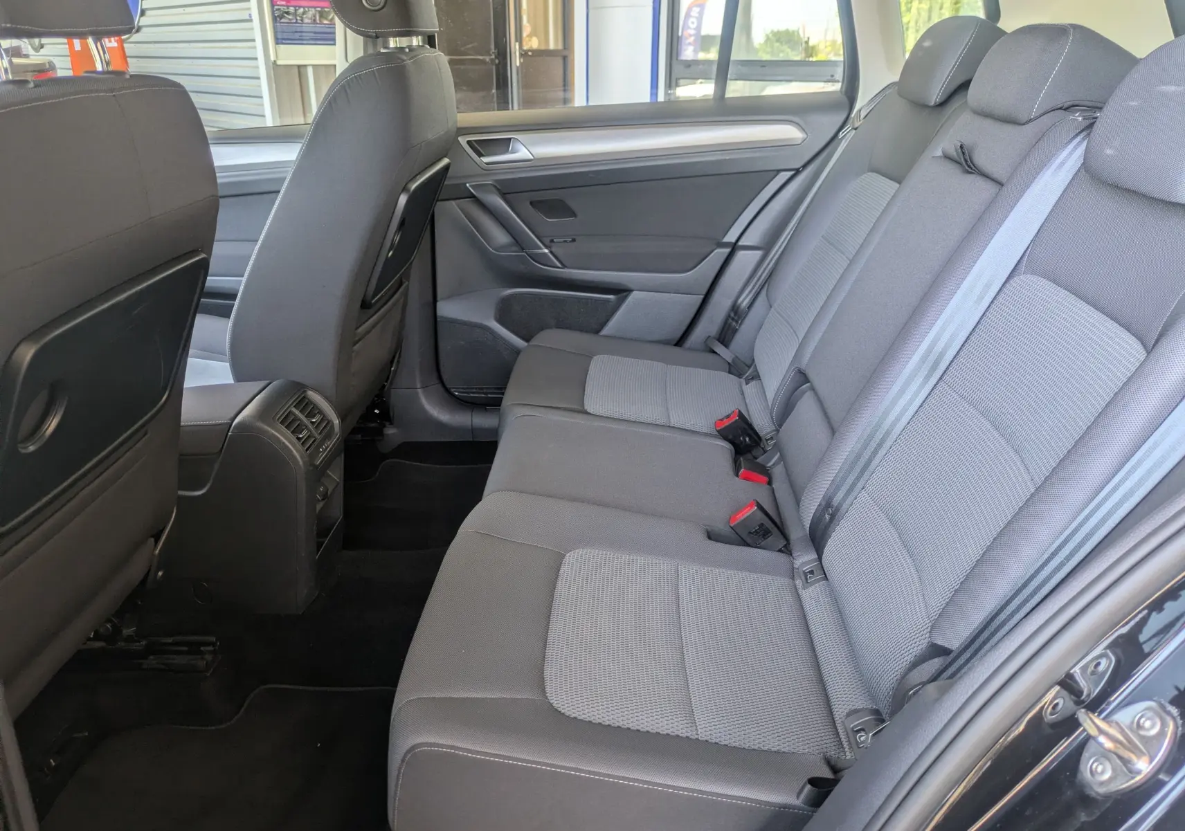 Vue intérieure côté droit des sièges arrière gris du Volkswagen Golf Sportsvan Confortline noir de 2014.