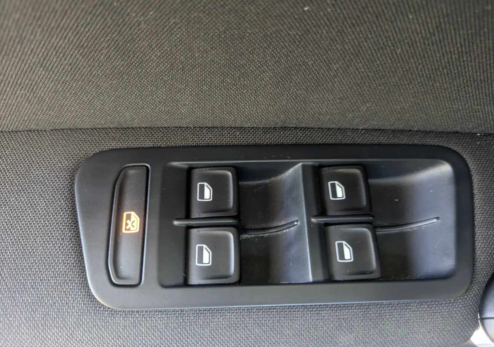 Boutons de commande des vitres électriques sur le panneau de porte intérieur d'une Volkswagen Golf Sportsvan noire.