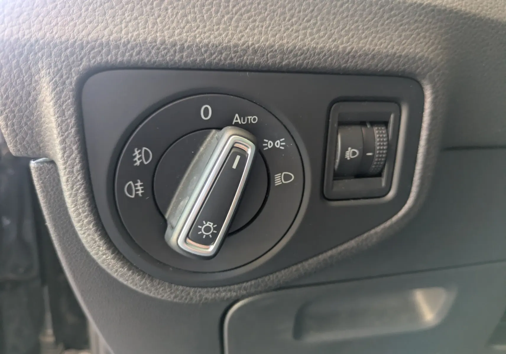 Gros plan sur le bouton de commande des phares dans l’habitacle noir d’une Volkswagen Golf Sportsvan 2014.