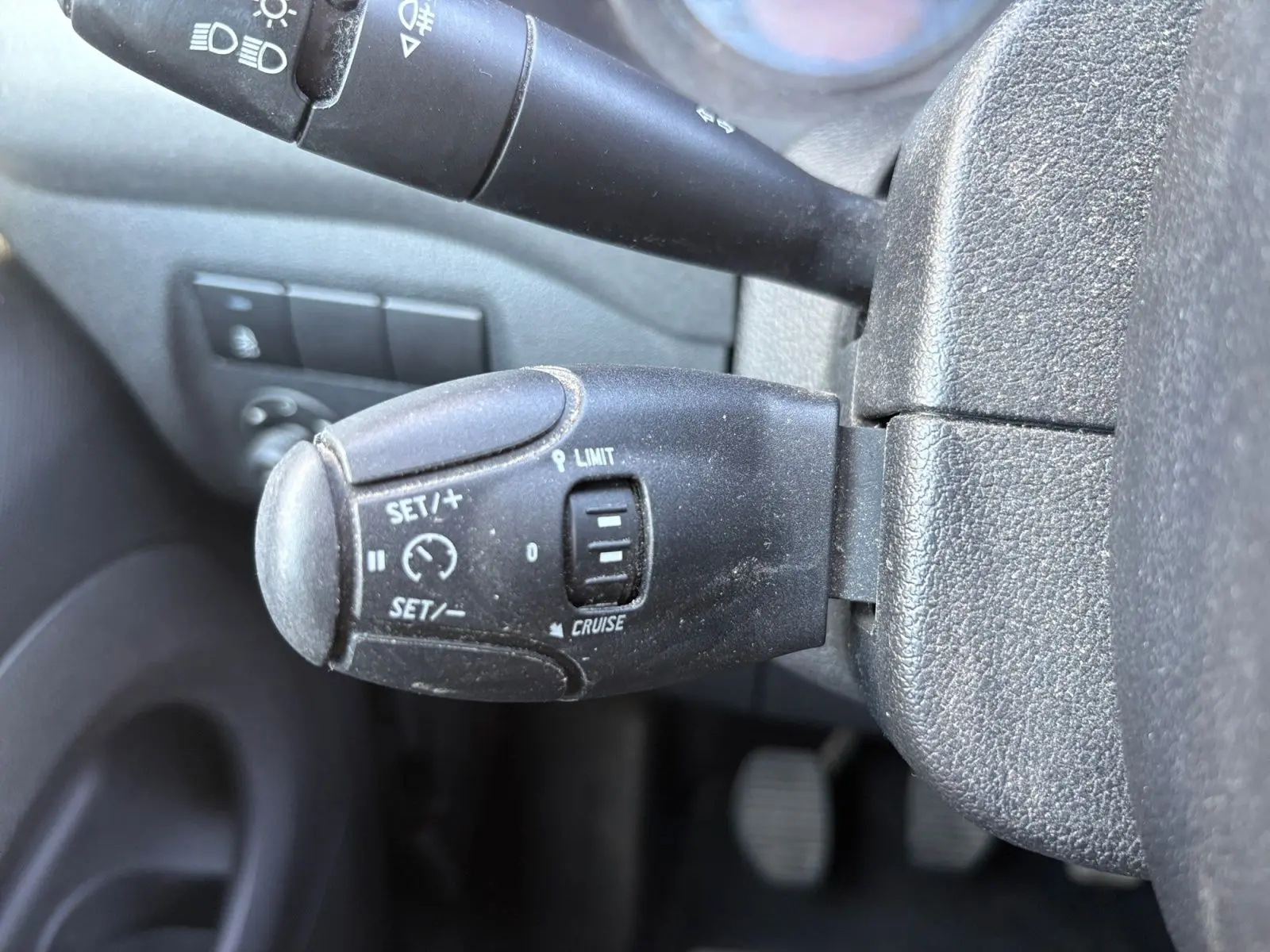 Gros plan sur la commande de régulateur et limiteur de vitesse du Peugeot Partner Tepee 2016, intérieur noir.