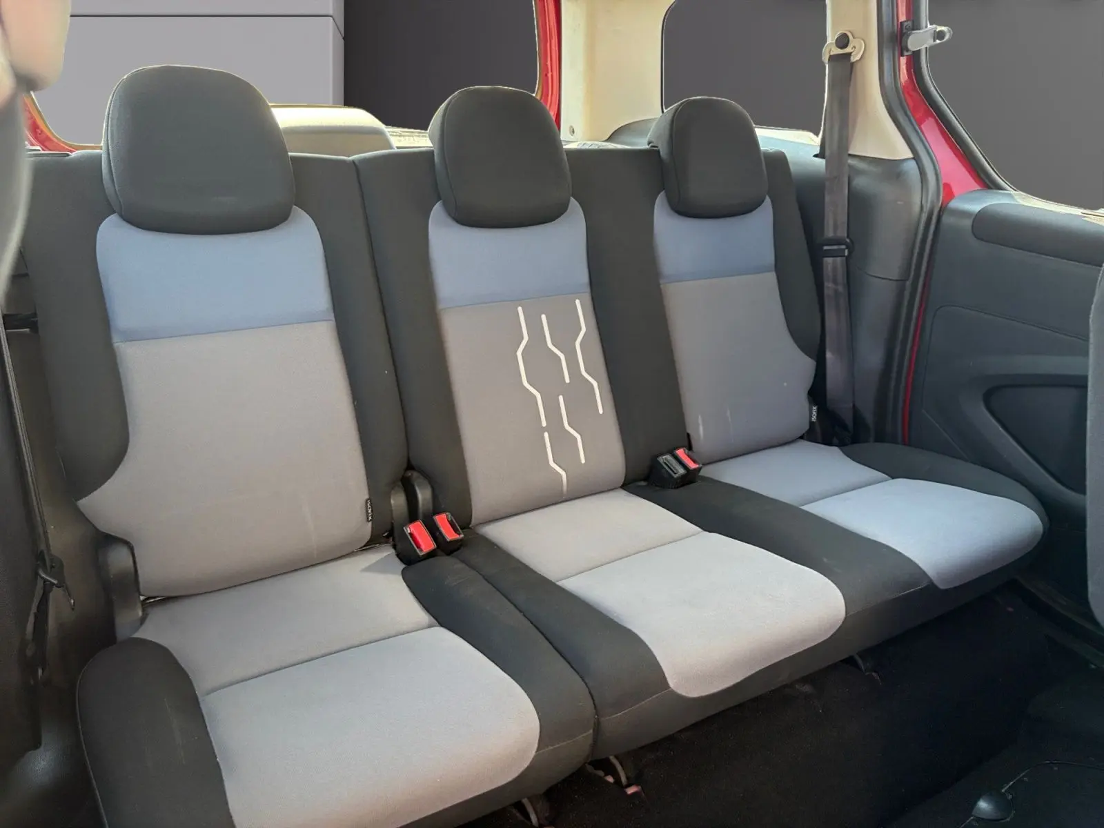 Vue intérieure sur la banquette arrière grise et noire du Peugeot Partner Tepee rouge, avec ceinture de sécurité visible côté droit.