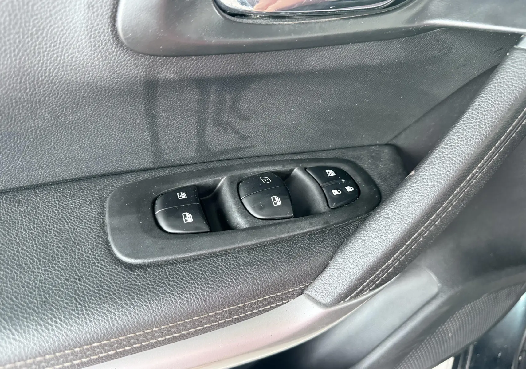 Gros plan sur les commandes de lève-vitres et verrouillage sur la porte côté conducteur du Renault Kadjar gris.