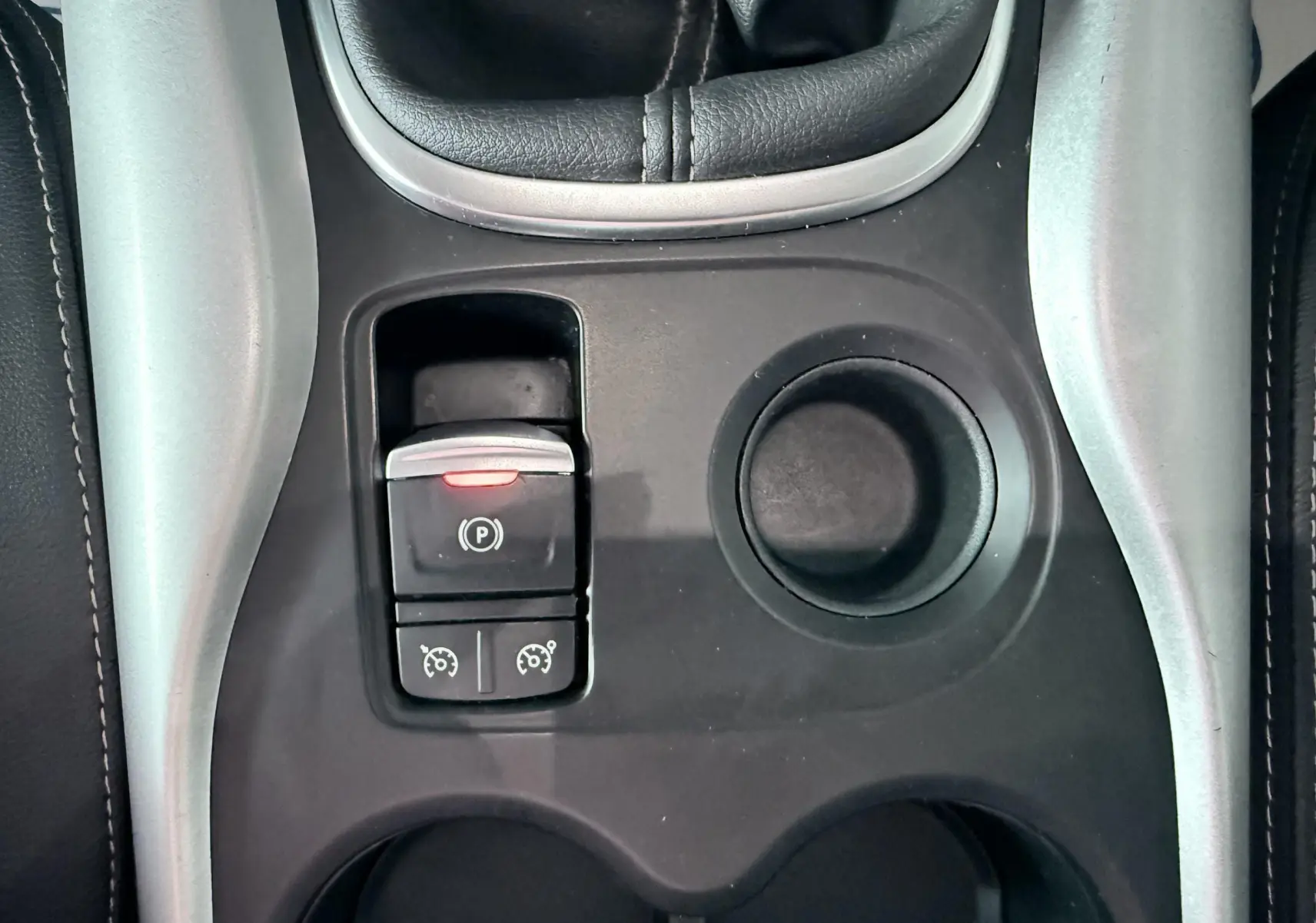 Gros plan sur la console centrale noire du Renault Kadjar gris, avec frein à main électronique et porte-gobelets.