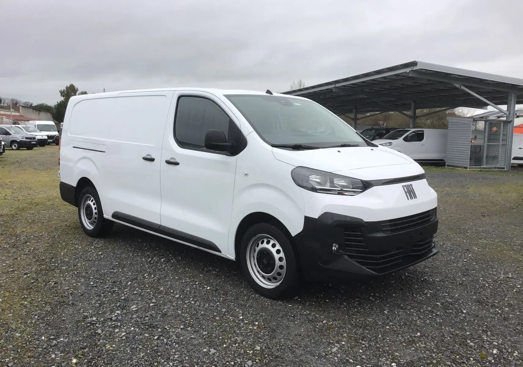 Fiat Scudo Fourgon blanc vu en 3/4 avant droit, avec pare-chocs noirs et jantes acier, sur parking extérieur.