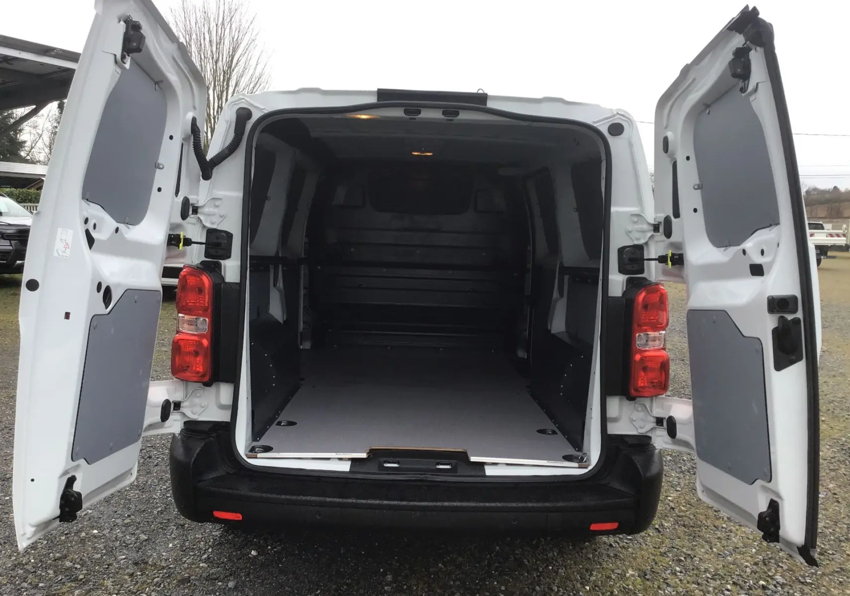 Vue arrière du FIAT Scudo Fourgon blanc 2024 avec portes ouvertes montrant l’espace de chargement vide et aménagé.