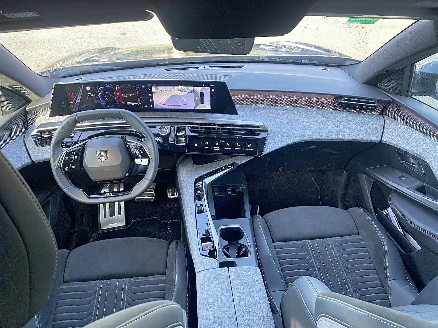 Vue intérieure avant du Peugeot 5008 Hybrid 145 GT e-dcs6 2025, tableau de bord moderne et sièges noirs avec console centrale grise.