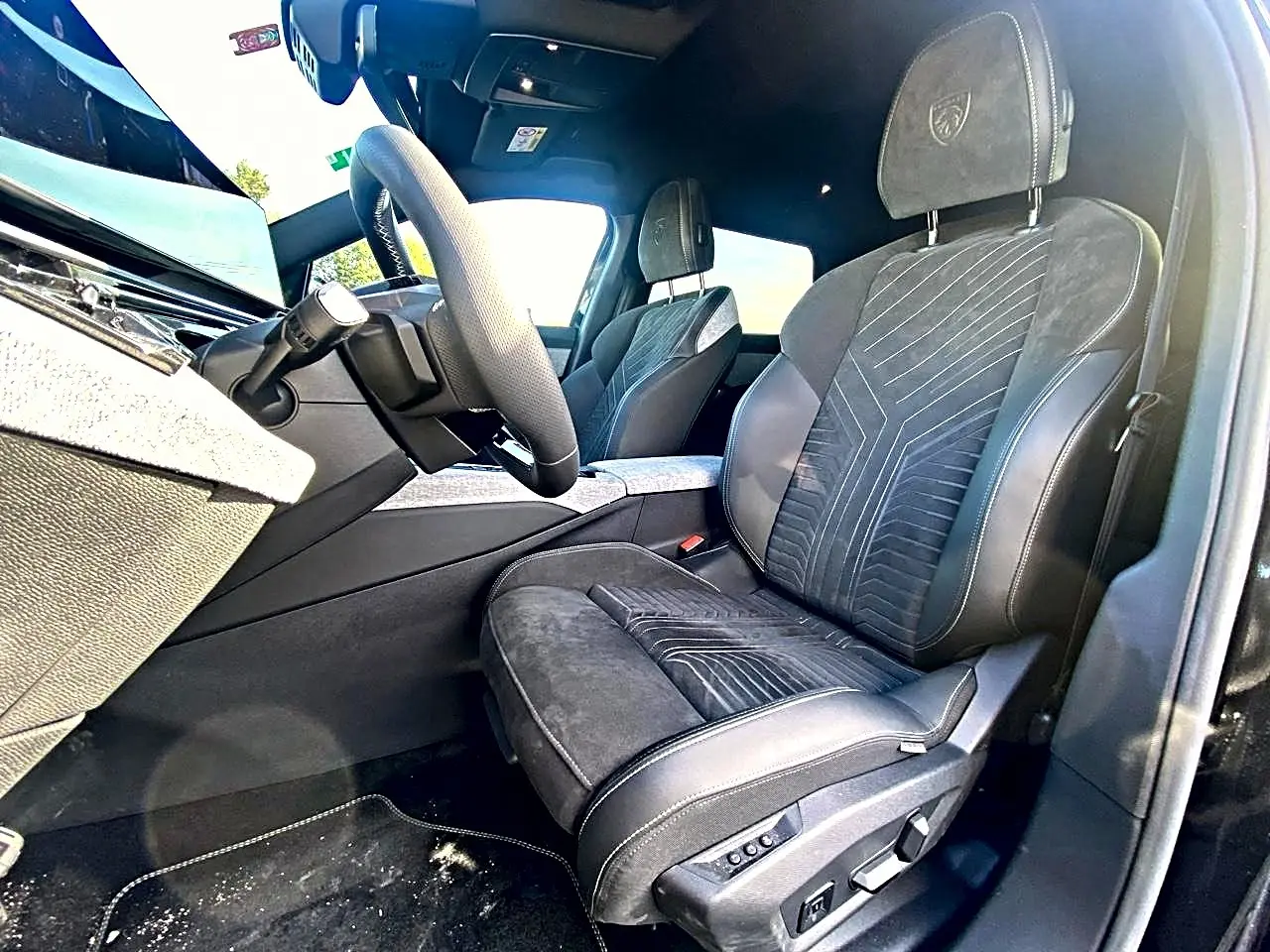 Vue intérieure côté droit des sièges avant noirs en cuir et alcantara avec logo Peugeot embossé sur les appuis-tête.