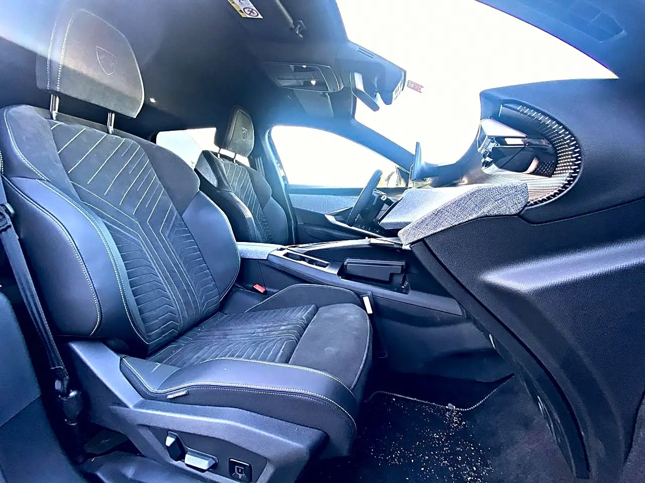 Vue intérieure côté passager avant du Peugeot 5008 Hybrid 145 GT e-dcs6 2025 avec sièges noirs et détails en tissu.