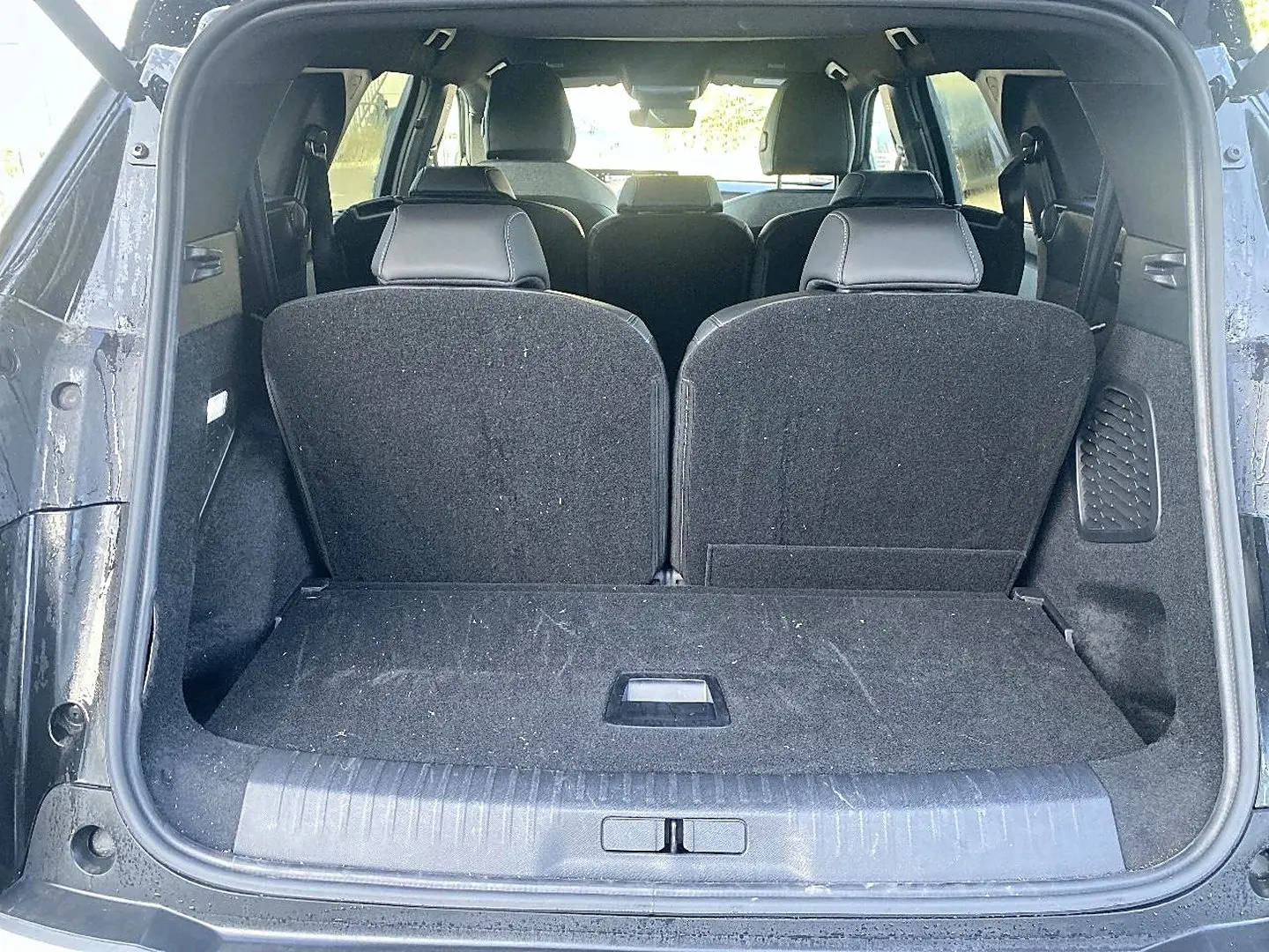 Vue arrière du coffre ouvert d’un Peugeot 5008 noir, montrant les sièges arrière relevés et l’espace de chargement.