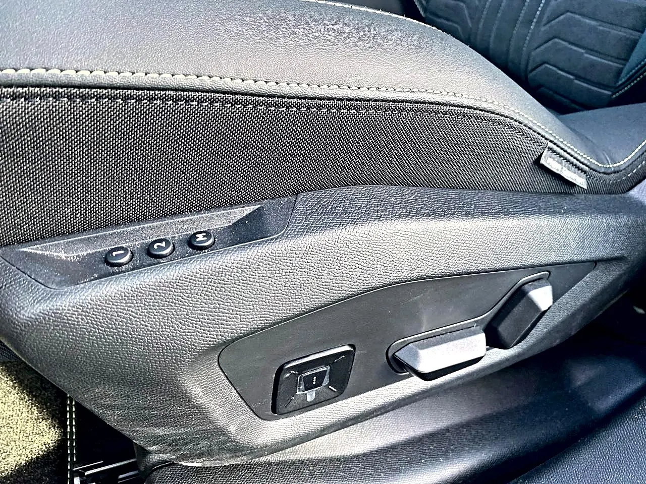 Gros plan sur les commandes de réglage électrique du siège conducteur noir du Peugeot 5008 Hybrid 145 GT e-dcs6.