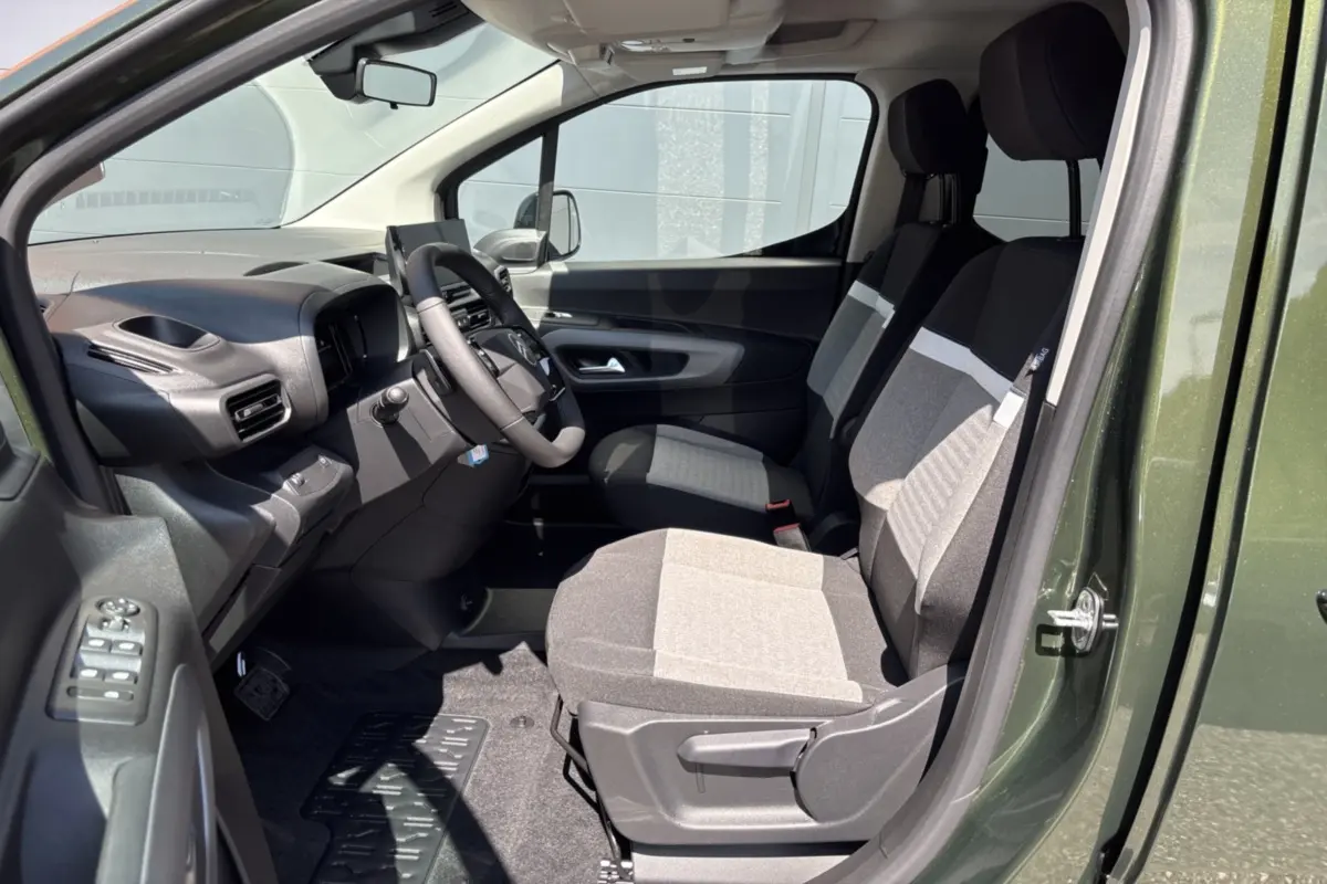 Vue intérieure côté conducteur du Citroën Berlingo 2026 Sirkka green, avec sièges tissu bicolores et tableau de bord noir.