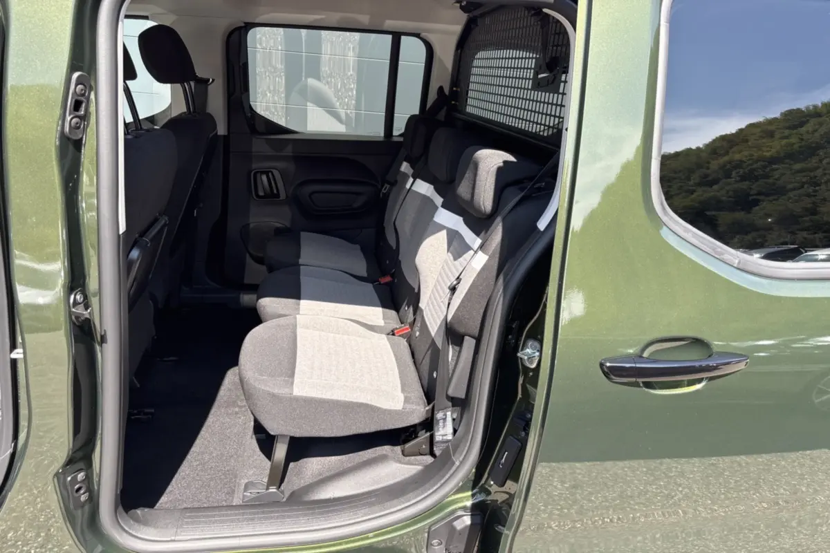 Vue intérieure côté droit arrière du Citroën Berlingo Sirkka green, montrant les trois sièges arrière indépendants et la grille de séparation.