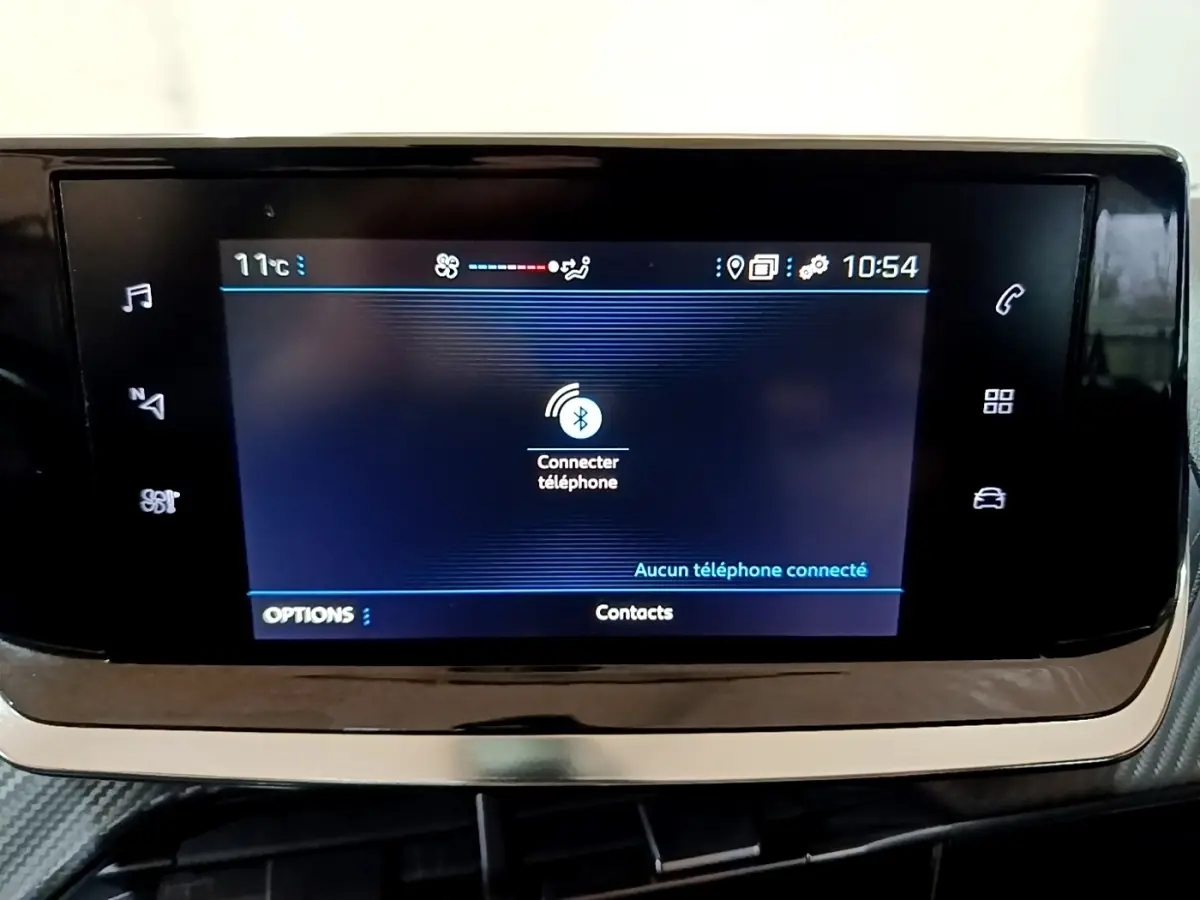 Écran tactile central de la Peugeot 208 noir, affichant la connexion Bluetooth au téléphone, vue de face rapprochée.