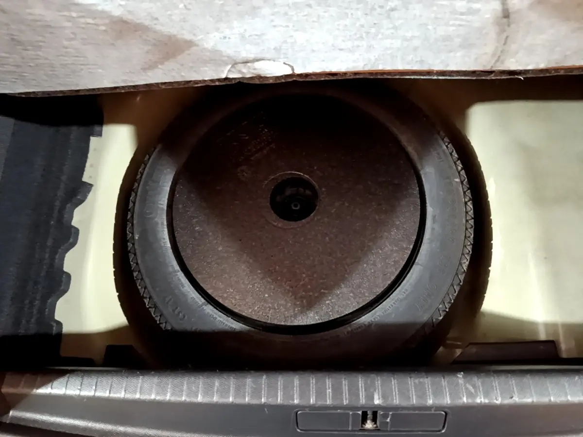 Vue plongeante sur la roue de secours noire logée dans le coffre d'une Peugeot 208 noire, version BlueHDi 100 S&S Active Business.